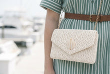 Person wearing a green and white striped dress with a white woven handbag.