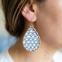 Teardrop-shaped earring with blue and white pattern worn by a person