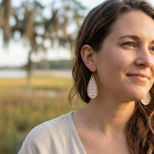 Woman wearing earrings outdoors with a blurred natural background
