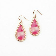 Teardrop-shaped earrings with pink and white pattern and gold frame on a white background