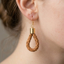 Close-up of a braided wooden earring with a gold accent on an ear.