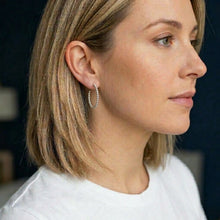 Close-up of a woman wearing a silver hoop earring with a blurred background