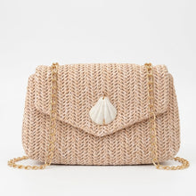 Beige woven handbag with a shell charm on a light gray background