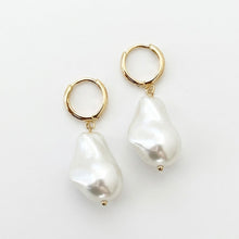 Pair of pearl earrings with gold hoops on a white background