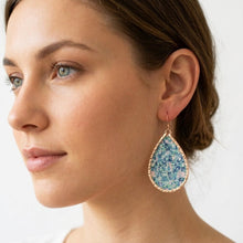Teardrop-shaped earrings with floral pattern worn by a model