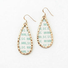 Gold teardrop earrings with a patterned interior on a white background