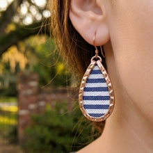 Teardrop-shaped earring with blue and white pattern worn by a person outdoors.
