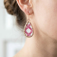 Earring with pink and white pattern worn by a person