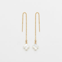 Gold chain earrings with white floral charms on a light gray background