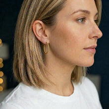 Woman wearing gold hoop earrings with a blurred background