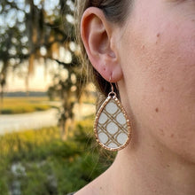 Close-up of a person wearing a decorative earring with a blurred natural background