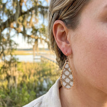 Close-up of a person wearing a teardrop earring with a natural background