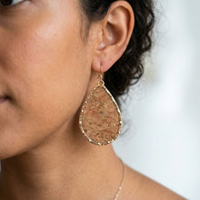 Teardrop-shaped cork earring on a person's ear with a blurred background