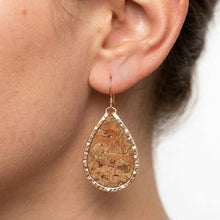 Teardrop-shaped earring with cork texture worn by a person
