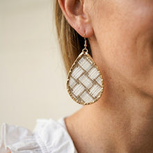 Teardrop-shaped earring with woven design worn by a person
