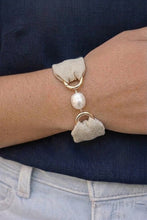 Bracelet with heart-shaped charms and a pearl on a wrist against a dark background