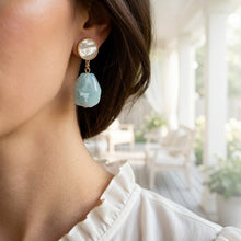 Close-up of a woman wearing earrings with a blurred indoor background