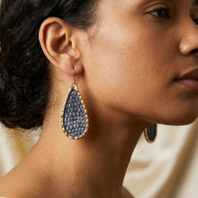 Close-up of a woman wearing textured earrings with a blurred background