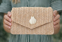 Knitted clutch with a shell decoration held by a person