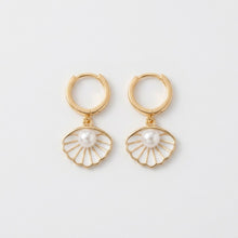 Gold hoop earrings with pearl center on a light gray background
