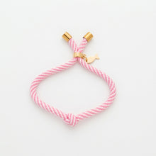 Pink braided bracelet with gold clasp on a white background