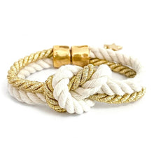 White and gold braided bracelet with a knot on a white background