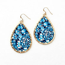 Teardrop-shaped earrings with blue floral pattern and gold frame on a white background