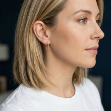Close-up of a woman wearing gold hoop earrings with a blurred background