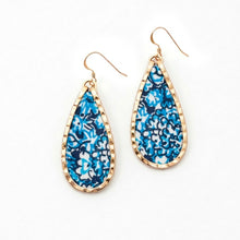 Teardrop-shaped earrings with blue floral pattern and gold frame on a white background