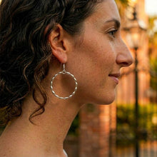 Woman wearing a silver hoop earring with a blurred natural background