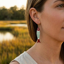 Woman wearing fish-shaped earrings with a blurred natural background
