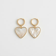 Heart-shaped earrings with gold frames on a light gray background