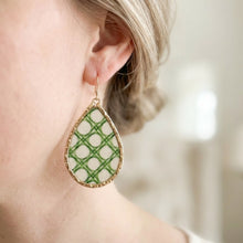 Teardrop-shaped earring with green pattern worn by a person
