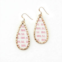 Teardrop-shaped earrings with gold frame and pink text on a white background