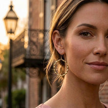 Woman wearing gold hoop earrings with a blurred street lamp and building in the background
